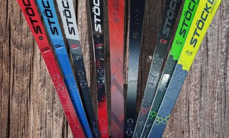 Eine Auswahl von Skiern der Marke Stöckli in verschiedenen Farben und Designs. Die Skier stehen auf einem Holzuntergrund. | © Austrian Ski- & Service Ranch | Trixi Leitner