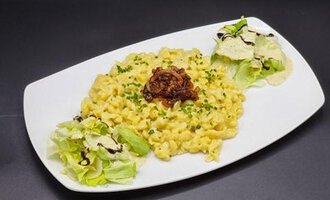 A plate of creamy macaroni and cheese, garnished with crispy onions. Next to it are fresh salad and a dressing.