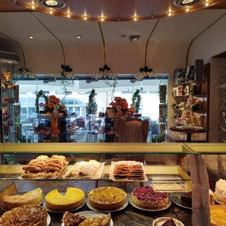 Eine gemütliche Bäckerei mit einer Auswahl an süßen und herzhaften Backwaren. Im Hintergrund sieht man Tische und Stühle für Gäste. | © Kleinwalsertal Tourismus | N. Lughammer