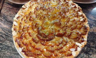 Ein köstlicher Pflaumenkuchen mit einer dekorativen Oberfläche. Der Kuchen hat eine goldene Farbe und ist mit Mandeln garniert. | © Kleinwalsertal Tourismus | N. Lughammer