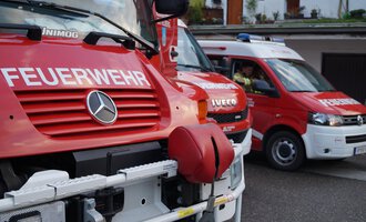 Ein rotes Feuerwehrfahrzeug steht neben einem Rettungswagen. Beide Fahrzeuge sind mit wichtigen Notfalldiensten gekennzeichnet. | © Feuerwehr Mittelberg | Christoph Hilbrand