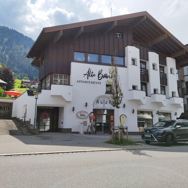 Ein modernes Gebäude mit Holz- und Putzfassade, das Apartments anbietet. Im Hintergrund sind grüne Berge und ein blauer Himmel zu sehen. | © Kleinwalsertal Tourismus | N. Lughammer