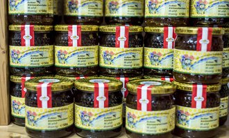 A variety of jars with jam is stacked. The jars have colorful labels with decorative designs. | © Kleinwalsertal Tourismus | Dominik Berchtold