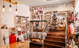 A cozy shop with festive decorations and many handmade products. Shelves are well-stocked and the atmosphere is inviting. | © Herzstichle | Ninja Matt