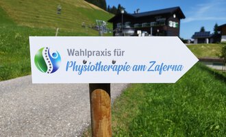 A sign points to the election practice for physiotherapy at Zaferna. The surroundings are green and mountainous, ideal for relaxation. | © Kleinwalsertal Tourismus | N. Lughammer