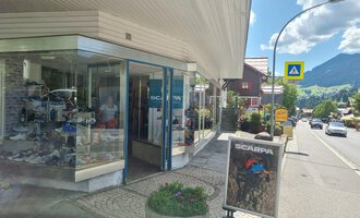 A store in the mountains with large display windows. Outside, there is a sign with the logo "Scarpa". | © Schuhhaus Schuster | Marietta Diehl