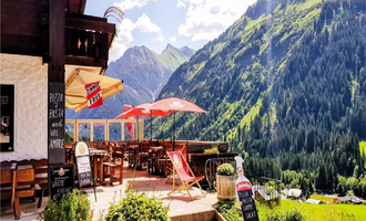 A cozy restaurant with outdoor seating and a view of the mountains. The surroundings are green and picturesque, ideal for a relaxing break. | © Starzelhaus Pizzeria La Marmotta | J. Reich-Ulicny