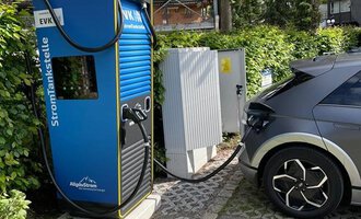 Eine Elektroladestation mit einem elektrischen Auto, das gerade aufgeladen wird. Die Umgebung ist grün und ruhig, umgeben von Bäumen. | © Energieversorgung Kleinwalsertal GmbH