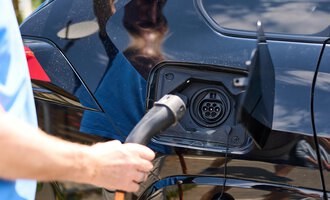 Ein Elektroauto wird aufgeladen. Ein Ladekabel wird in die Ladebuchse gesteckt. | © Kleinwalsertal Tourismus | Oliver Farys