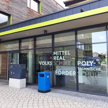 A modern school building with large windows. The entrance facade displays the labeling of different types of schools. | © Kleinwalsertal Tourismus | Veronika Senn