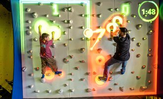 Zwei Kinder klettern an einer interaktiven Kletterwand mit bunten Lichtern. Die Zeit läuft ab und es gibt verschiedene farbige Griffe. | © Wonniland Sonthofen | interSPA Gruppe