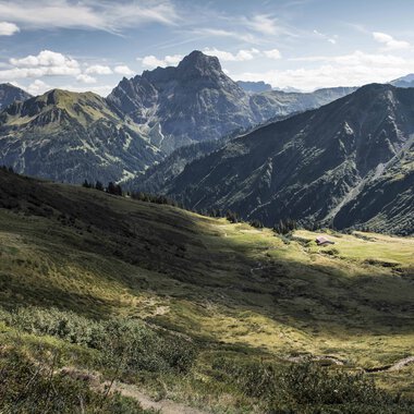Wide view of green mountains and valleys in the Black Forest with mountains in the background on a sunny day. | © Kleinwalsertal Tourismus eGen • Photographer: Andre Tappe