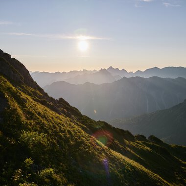 Landscape in Kleinwalsertal at sunset, with mountains and green hills in the foreground. | © Kleinwalsertal Tourismus eGen • Photographer: Oliver Farys