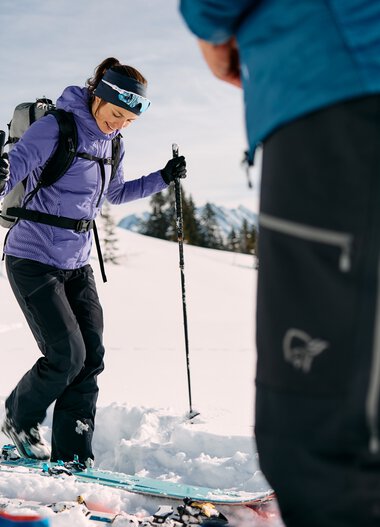 Woman ski touring in snowy mountain landscape with a companion, equipped with skis and touring gear. | © Kleinwalsertal Tourismus eGen • Photographer: Oliver Farys