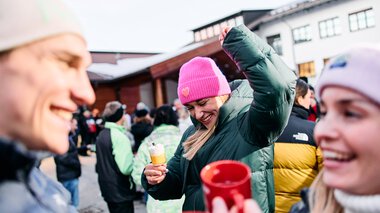 Fröhliche Menschen beim Schneemanntreffen im Kleinwalsertal, einige trinken heiße Getränke | © Kleinwalsertal Tourismus eGen • Fotograf: Oliver Farys