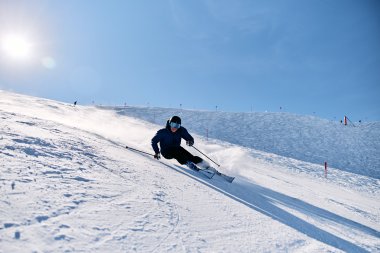 A skier in dark clothing and goggles skiing down a steep snowy slope. | © Kleinwalsertal Tourismus eGen • Photographer: Oliver Farys