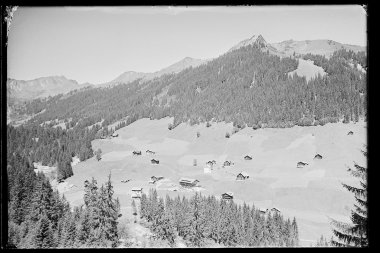 Historisches Schwarz-Weiß-Foto von Baad im Kleinwalsertal, mit Bergen und einzelnen Häusern in der Landschaft. | © Kleinwalsertal Tourismus eGen • Karl Max Kessler Archiv