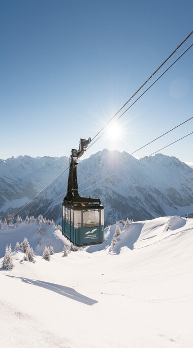 Gondola lift in a winter landscape with snow-covered mountains and clear sunlit sky. | © Oberstdorf · Kleinwalsertal Bergbahnen