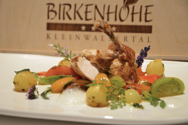 Plated dish with seasoned meat, vegetables, sauce, garnished with herbs and lavender flowers. | © Kleinwalsertal Tourismus eGen • Birkenhöhe