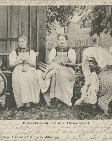 Vier Frauen in traditioneller Tracht sitzen draußen im Garten und arbeiten an verschiedenen Handarbeiten. | © Kleinwalsertal Tourismus eGen