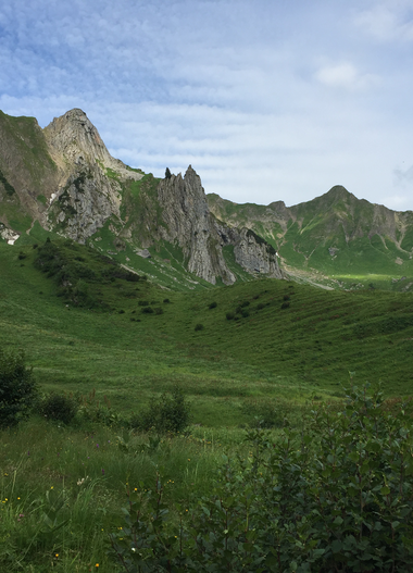 Grüne Wiesen im Bärguntal mit Bergen im Hintergrund, wolkiger Himmel, Sommer im Kleinwalsertal. | © Kleinwalsertal Tourismus eGen