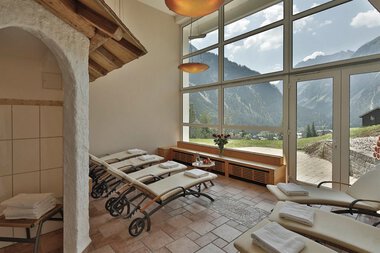 Innenraum eines Entspannungsbereichs mit Liegen, großen Fenstern und Bergblick, im Hotel »Alte Krone«. | © Alte Krone